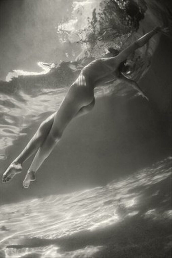 une femme se lève sous l'eau et tend ses bras vers le ciel